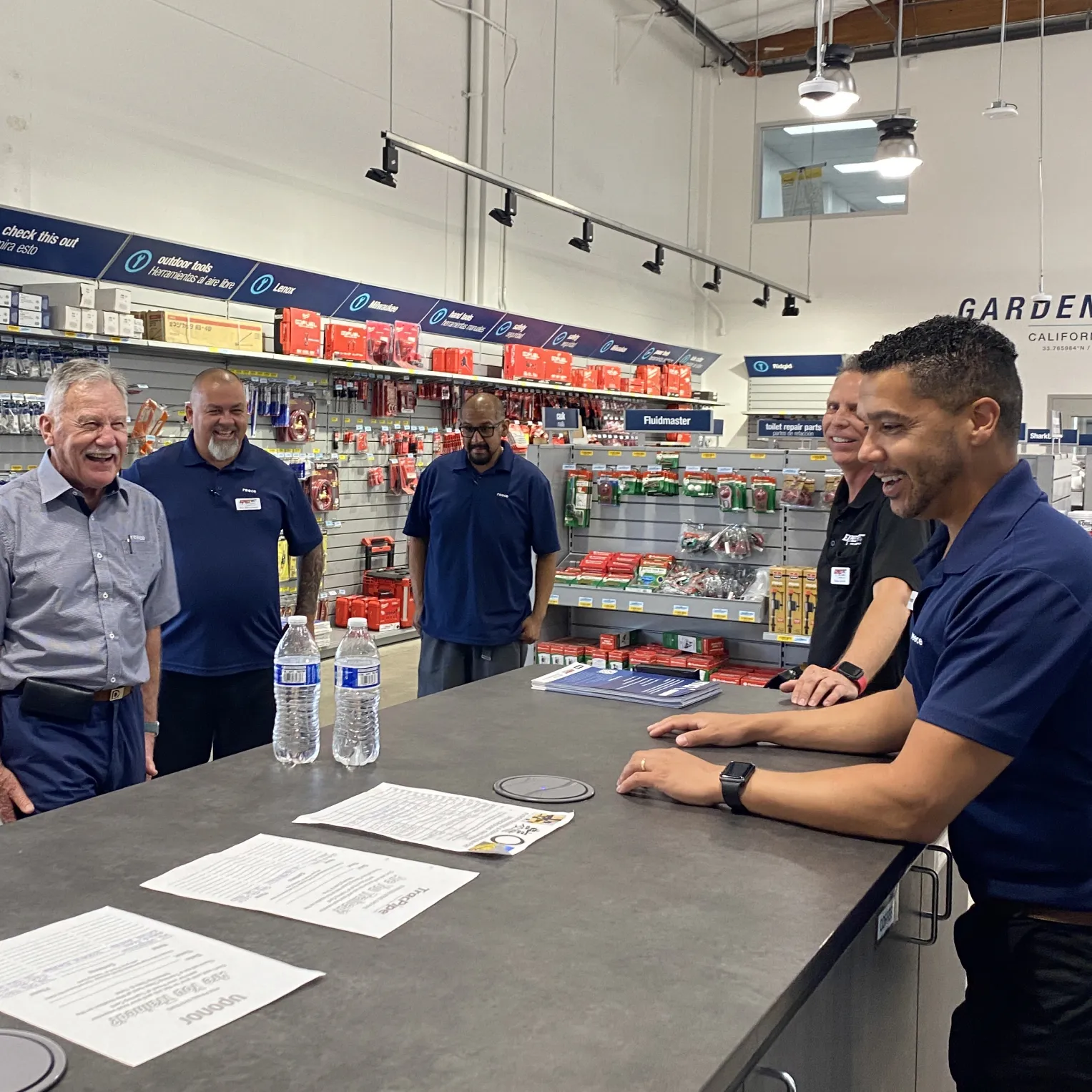 Reece team members in navy polos laughing together around a counter in a branch
