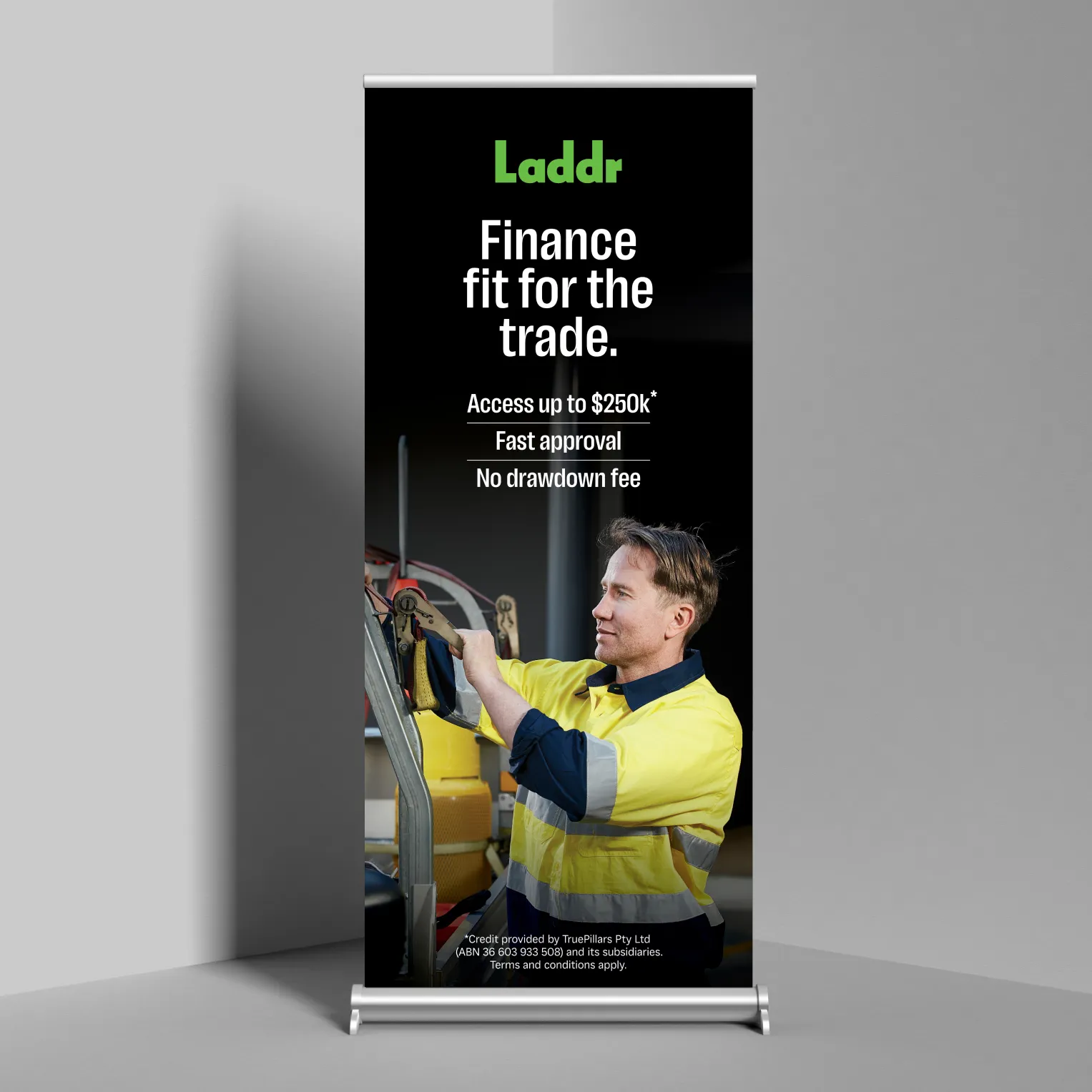 A Laddr pull-up banner reading “Laddr. Finance fit for the trade. Access up to $250k*. Fast approval. No drawdown fee”, above a photo of a tradie in yellow hi-vis