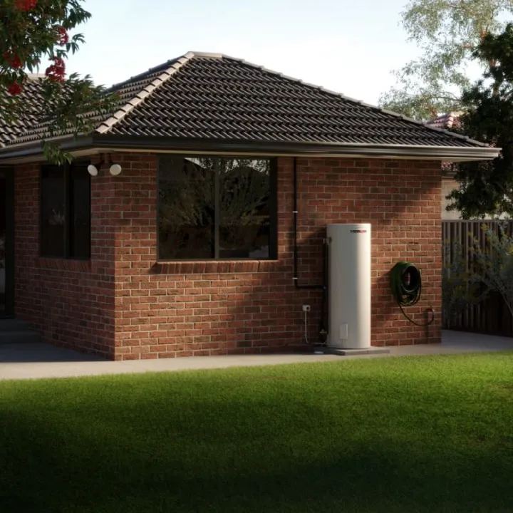 A brick house at dusk with a Thermann hot water tank mounted on its side wall