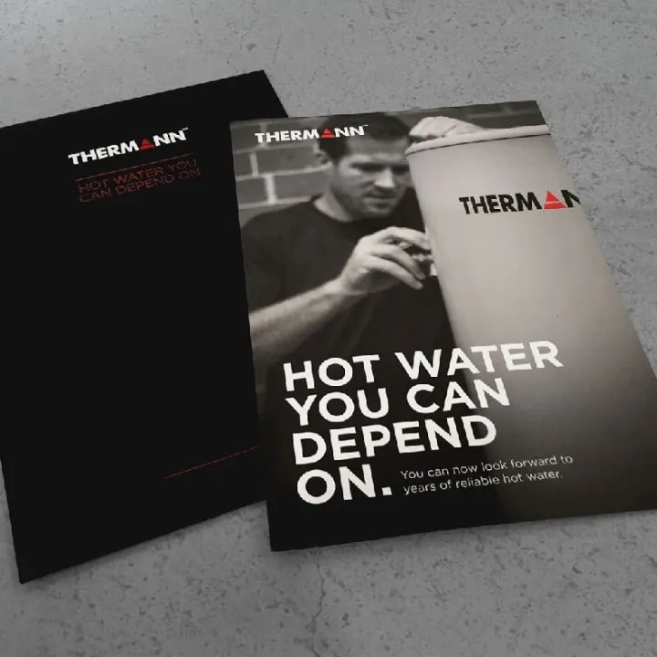 Two Thermann handbooks on grey concrete, one reading “Hot water you can depend on. You can now look forward to years of reliable hot water.”