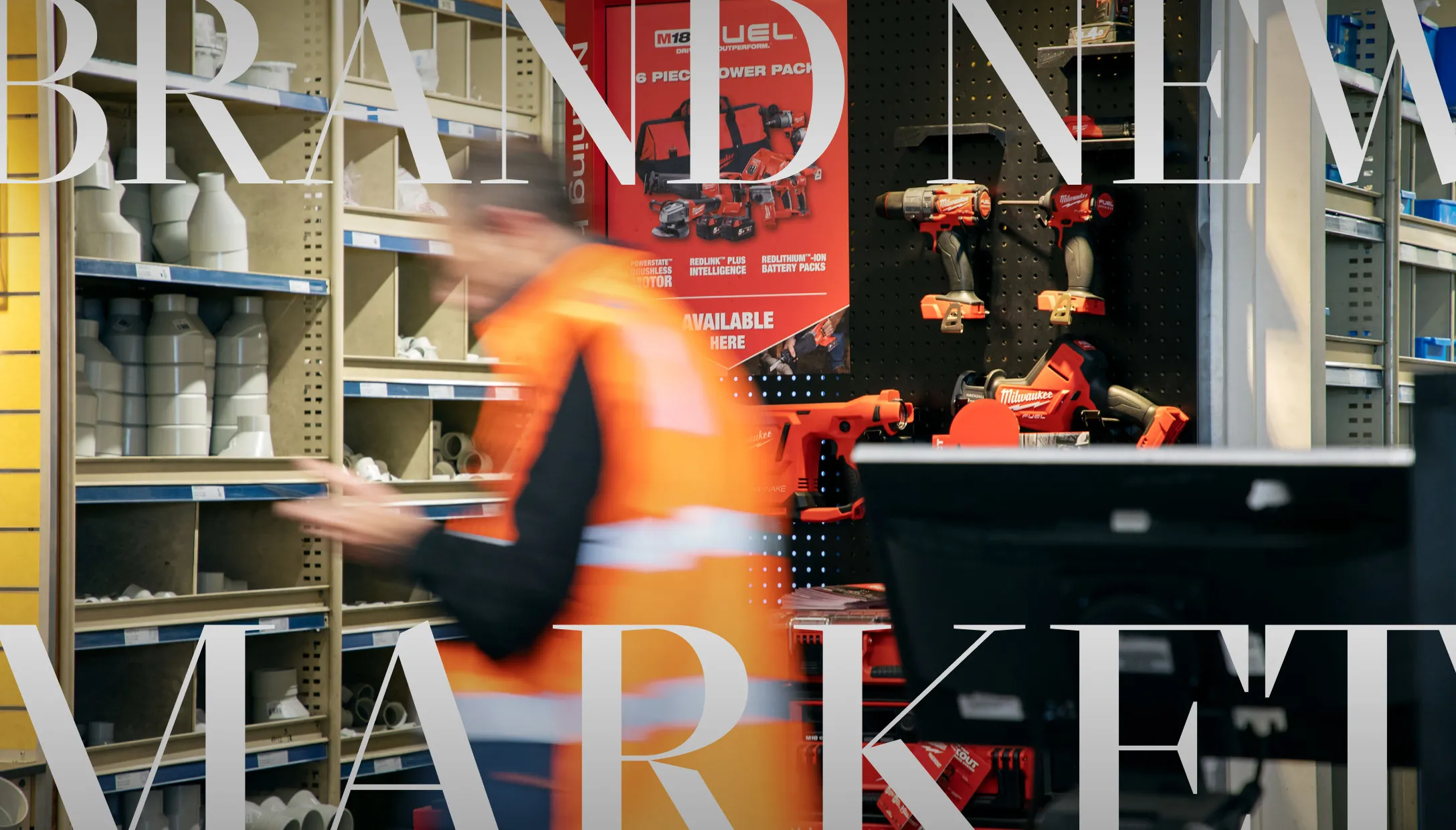The words “Brand new market” over a Reece store, where a worker in hi-vis hurries past shelves of plumbing fittings and power tools