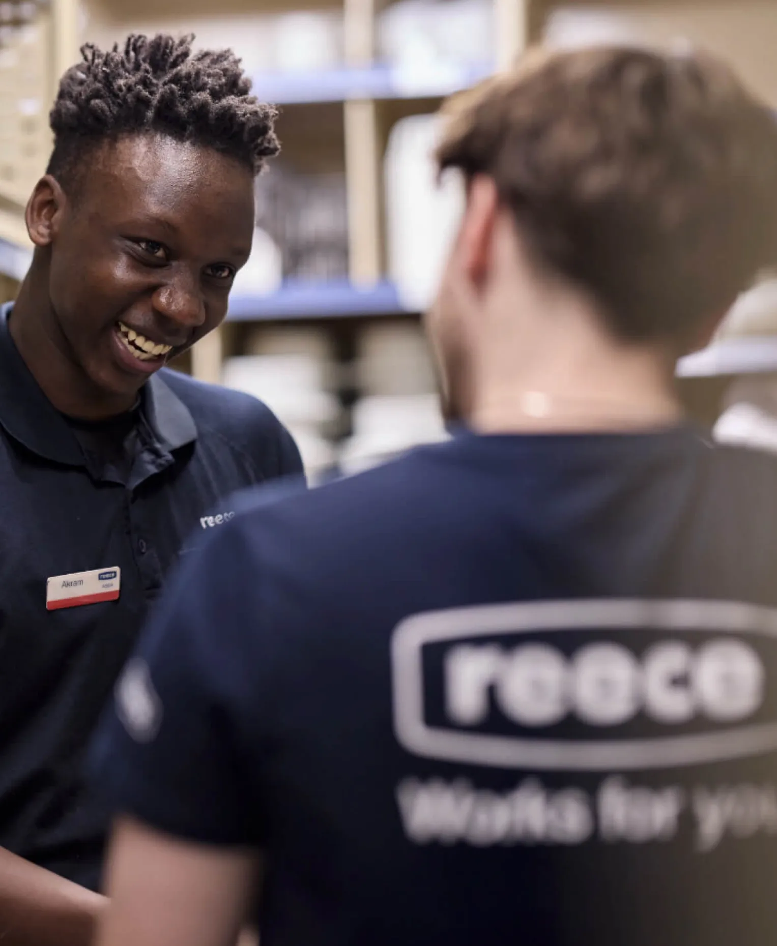 A smiling Reece team member chatting with a customer in a navy “Reece Works for you” t-shirt