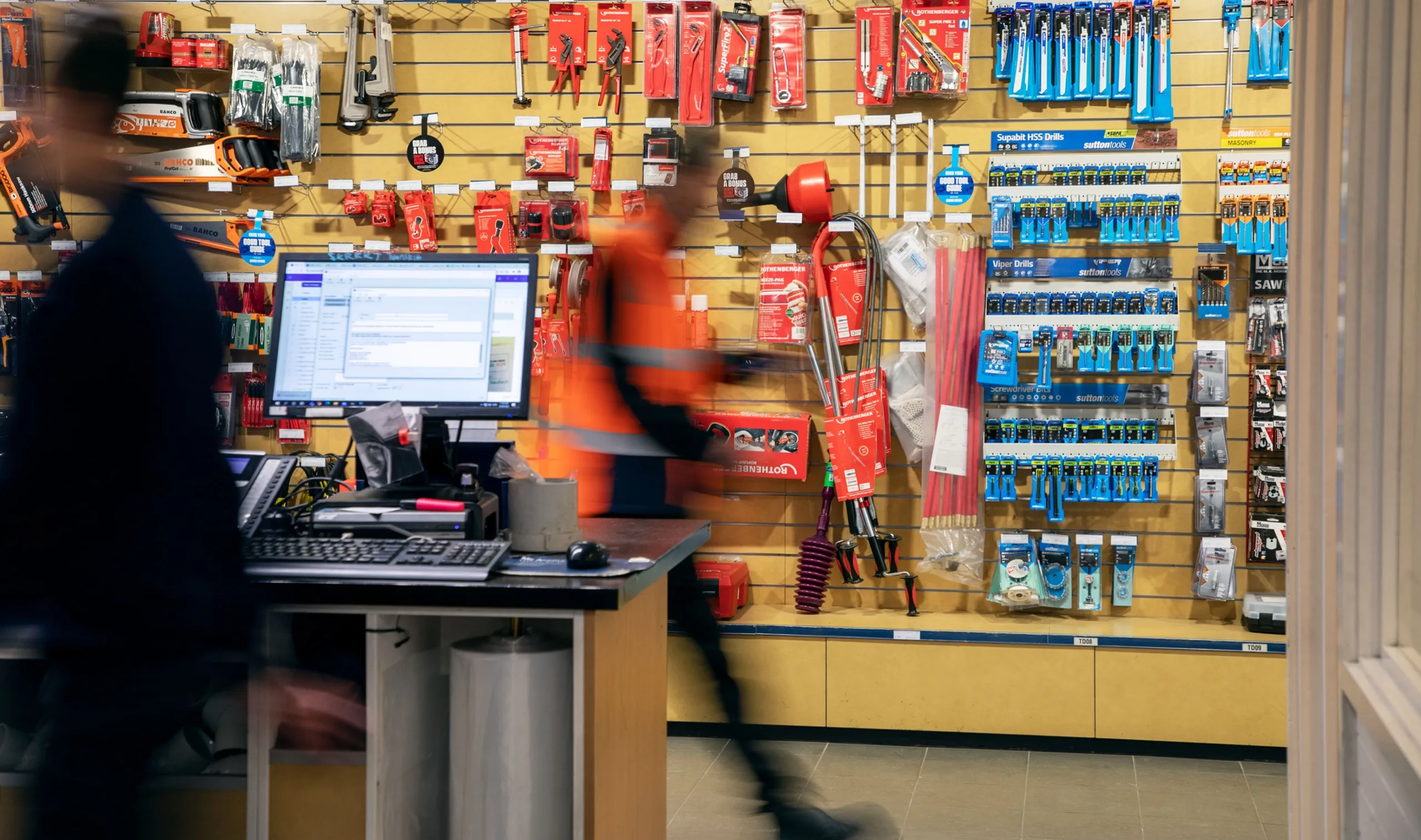 Tradies blurred in motion past the counter of a trade supply store